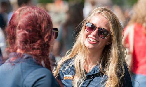 a Carroll University student wearing sunglasses smiling at another student.